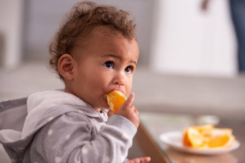 baby eating orange fruit. - food stock pictures, royalty-free photos & images