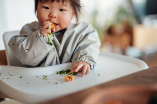 baby girl learning to feed herself with finger foods - food stock pictures, royalty-free photos & images