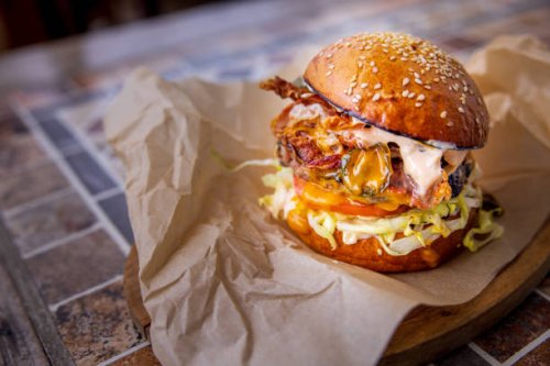 bacon cheeseburger with salad in bun, served on wooden board - junk food stock pictures, royalty-free photos & images