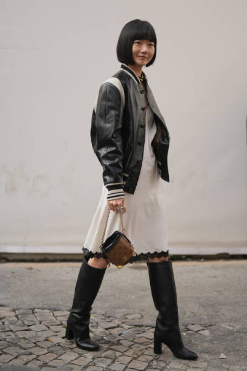 Bae Doona wears a black and white leather teddy jacket, a white knee long dress with lace borders, a brown monogram leather LV bag, knee high leather...