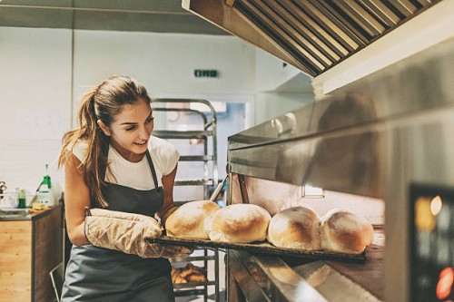 baker pulling a tray with hot bread - food stockfoto's en -beelden