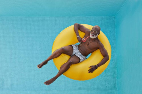 bald man relaxing in yellow inflatable ring - travel stock-fotos und bilder