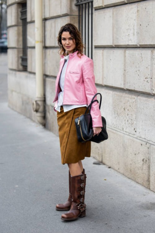 Bambi Northwood Blyth wears pink jacket, brown suede skirt, black bag, knee high boots outside Miu Miu during the Womenswear Fall/Winter 2025/2026 as...