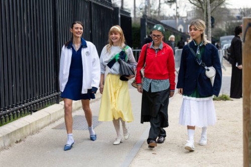 Barbara Ines wears a white jacket, a blue mini polo dress, white socks, blue heeled slingback and a white leather bag, in the middle a guest wears a...