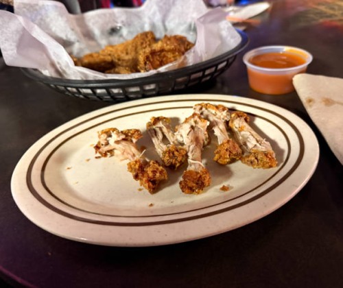 basket of bone in deep fried wings with discards after eating - junk food stock pictures, royalty-free photos & images