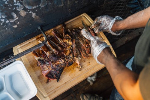 bbq chef cutting smoked pork ribs for his food truck or catering company - junk food stock pictures, royalty-free photos & images