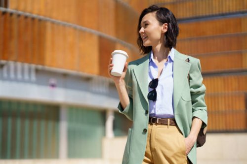 beautiful businesswoman with hand in pocket holding reusable coffee cup - junk food stock pictures, royalty-free photos & images