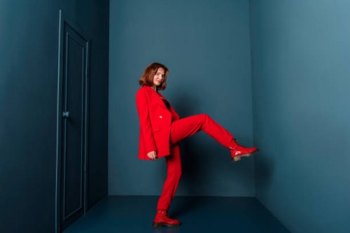 beautiful fashionable woman walking in a room with a door in a red suit indoors. concept - fashion stock-fotos und bilder