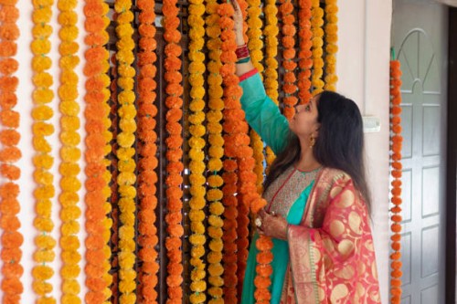 beautiful lady hanging marigold garlands on door. - home decoration stock pictures, royalty-free photos & images