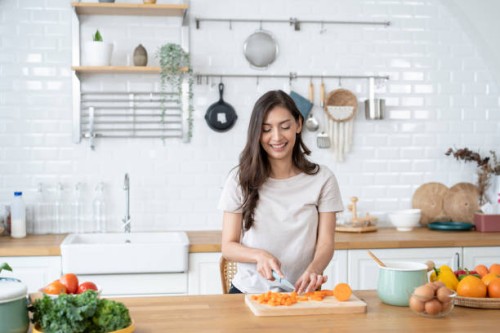 beautiful woman cutting ingredients for a meal in the kitchen - food stock pictures, royalty-free photos & images