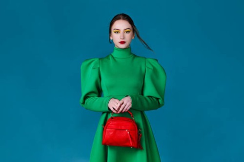 beautiful woman in green dress holding a red handbag - fashion stock pictures, royalty-free photos & images
