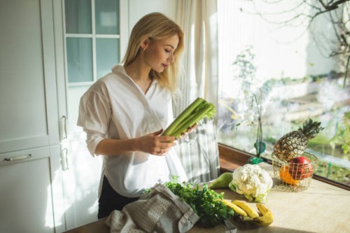 beautiful woman unpacks a full fabric bag with fruits and vegetables on the kitchen. - food stock pictures, royalty-free photos & images