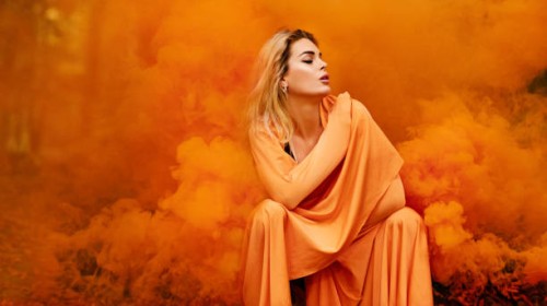 beautiful young blond female woman dancing and posing in orange smoke in outdoor countryside setting - fashion stock pictures, royalty-free photos & images