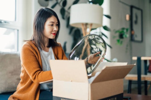 beautiful young woman unpacking parcel purchased online - home decoration stock pictures, royalty-free photos & images