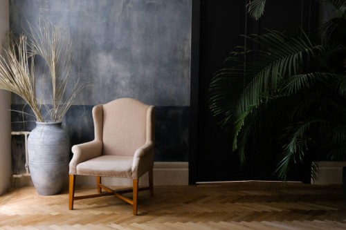 beige chair and a large vase near the window in the hall, next to a palm tree near the door. - home decoration stock pictures, royalty-free photos & images