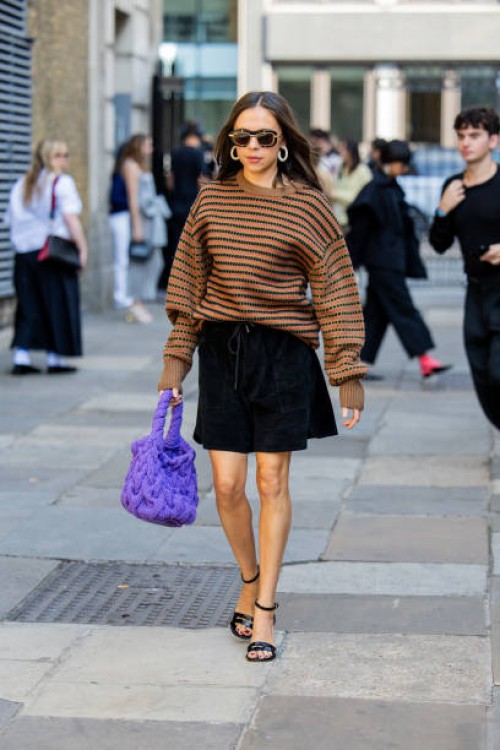 Bel Powley wears purple bag, brown black striped jumper, black skirt outside JW Anderson during London Fashion Week September 2024 on September 15,...