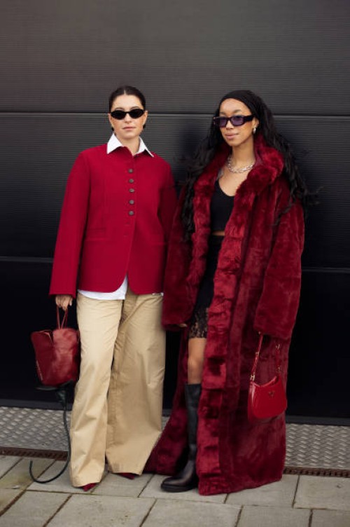Benthe Liem wears beige wide pants, a white shirt, a red cardigan, and a tulip flower-shaped bag and Amaka Hamelijnck wears a black lace skirt, black...