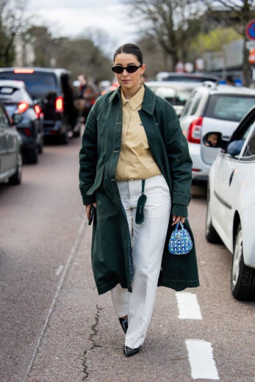 Benthe Liem wears green coat, beige button shirt, white pants, blue bag outside Lacoste during the Womenswear Fall/Winter 2024/2025 as part of Paris...
