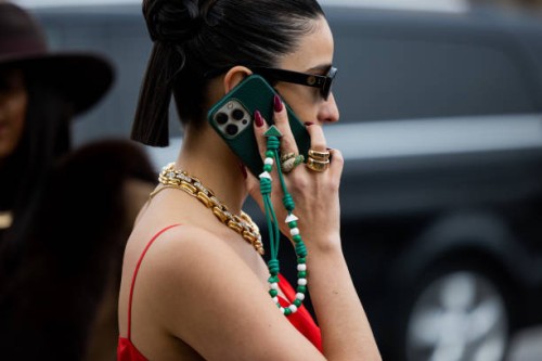 Bettina Looney talking on the phone wears sunglasses, golden necklace, red dress outside Prada during the Milan Fashion Week Womenswear Fall/Winter...