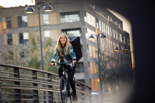 bicycle delivery woman with food backpack cycling in residential area - junk food stock pictures, royalty-free photos & images