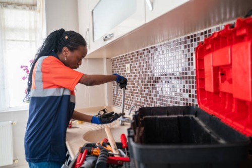 black female plumber fixing a leak in the kitchen sink of a house - home decoration stock pictures, royalty-free photos & images