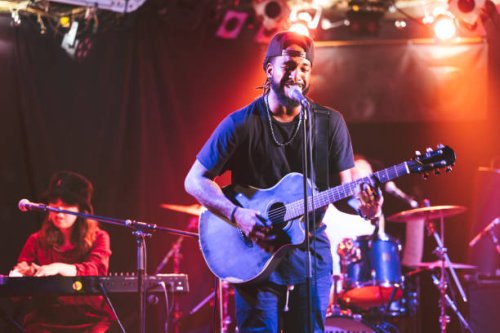 black male guitarist singing and playing acoustic guitar on stage - concert stock pictures, royalty-free photos & images