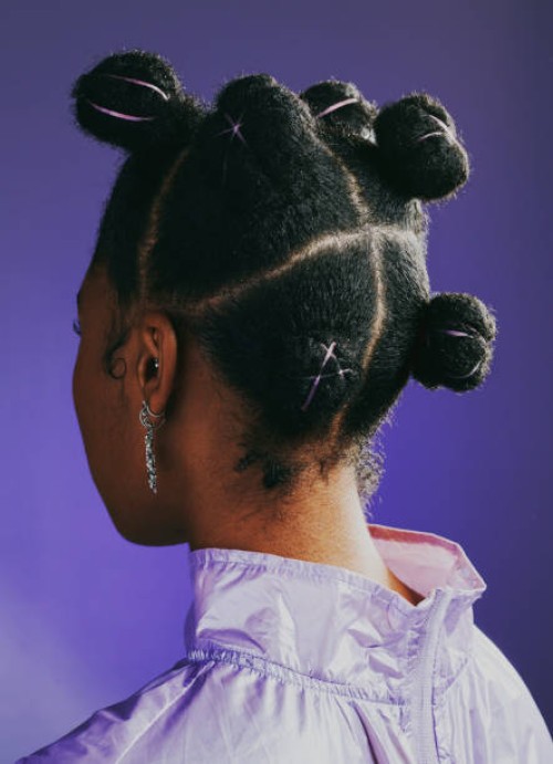 black woman standing against a purple studio background and showing her trendy and funky new hairstyle from behind. one female showing the back of her head with a creative and stylish hairdo - fashion stock pictures, royalty-