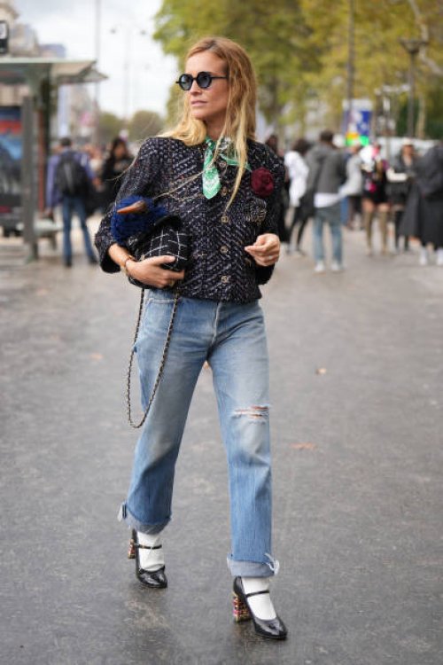 Blanca Miro wears sunglasses, a green scarf, a tweed knit jacket, a black striped Chanel bag, ripped jeans, white socks, high heels shoes, outside...