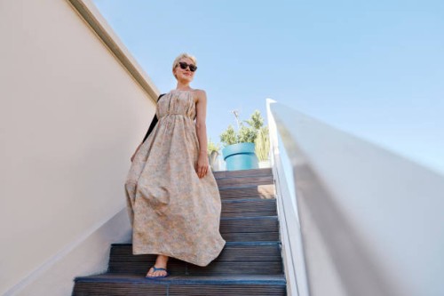 blond woman moving down steps outside cafe under blue sky - fashion stock pictures, royalty-free photos & images