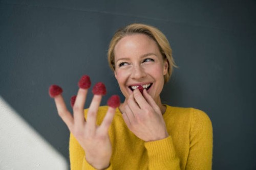 blond woman with raspberries on her fingers, laughing - food stock pictures, royalty-free photos & images