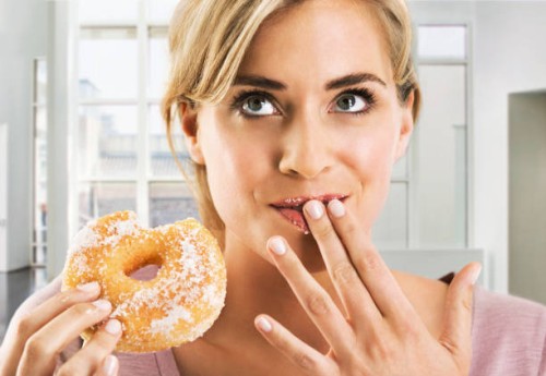 blonde woman eating a sugar coated doughnut - junk food stock pictures, royalty-free photos & images
