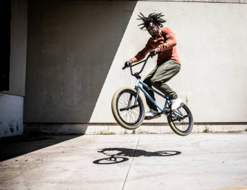 bmx rider performing jump in outdoor industrial environment - fashion stock pictures, royalty-free photos & images