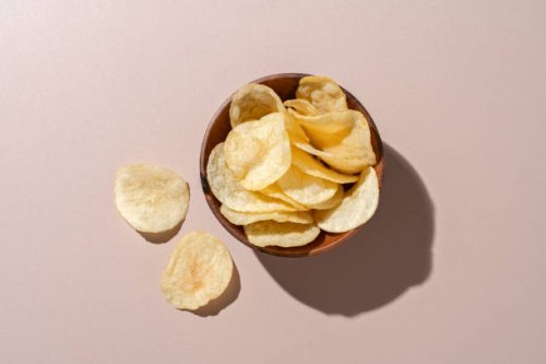 bowl of potato chips on brown background - junk food stock pictures, royalty-free photos & images
