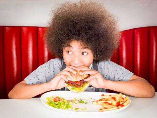 boy (10-11) eating hamburger in american diner - junk food stock pictures, royalty-free photos & images