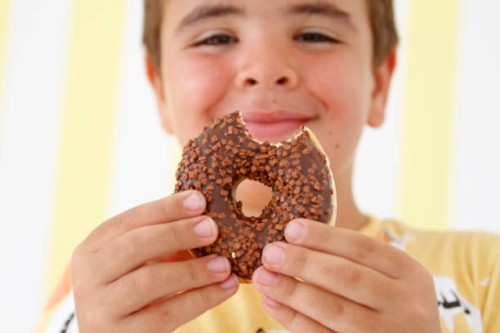 boy holding fresh sweet glazed donut in hands - junk food stock pictures, royalty-free photos & images