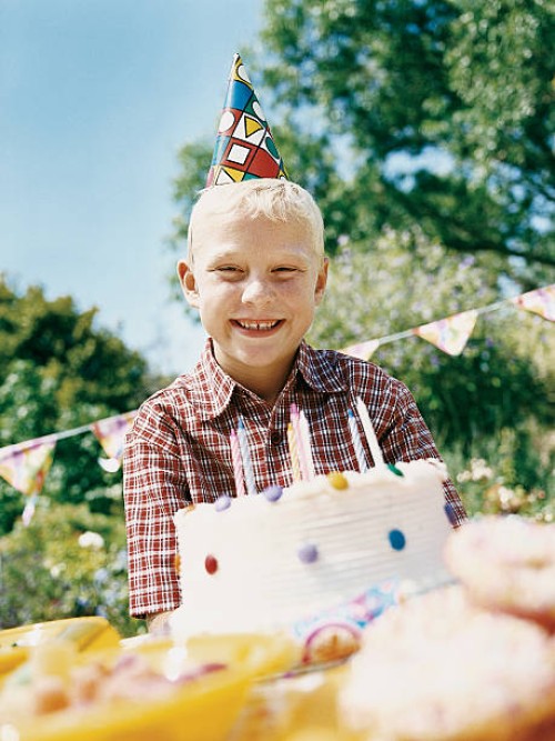 boy smiling and sitting at table with his birthday cake - garden decoration stockfoto's en -beelden
