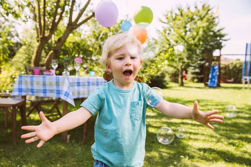 boy trying to catch soap bubbles in garden - garden decoration stock pictures, royalty-free photos & images