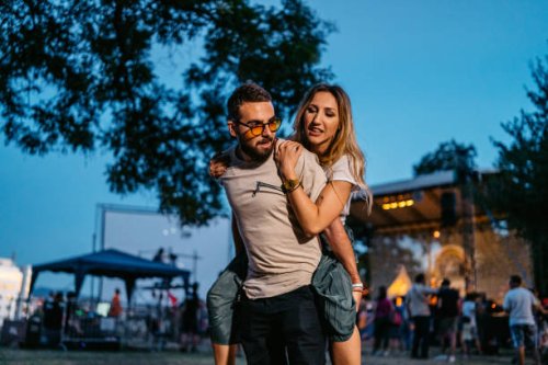 boyfriend giving his girlfriend a piggyback ride at the music festival - concert stock pictures, royalty-free photos & images
