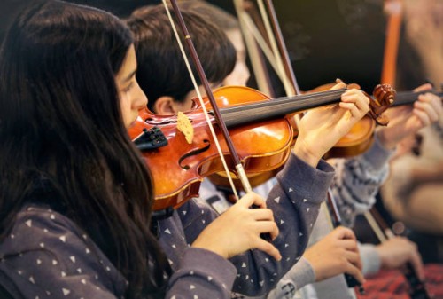 brunette girl playing the violin in a children's music band - concert stock pictures, royalty-free photos & images