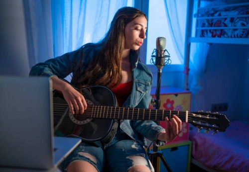 brunette teen singer girl singing in microphone playing guitar teleconferencing - concert stock pictures, royalty-free photos & images