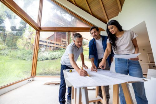 building contractor looking at blueprints with a couple remodeling their house - home decoration stock pictures, royalty-free photos & images