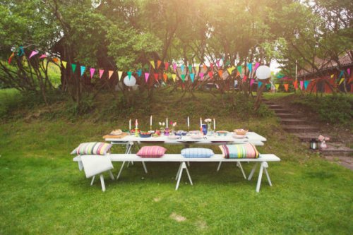 buntings hanging over food served on decorated picnic table at back yard - garden decoration stock pictures, royalty-free photos & images