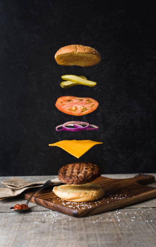burger with separated floating ingredients on black background. - junk food stock pictures, royalty-free photos & images