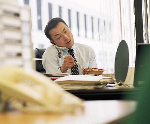 businessman eating lunch at desk, using mobile phone - junk food stock pictures, royalty-free photos & images