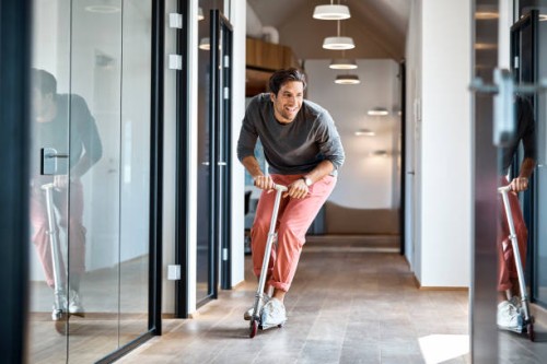 businessman enjoying on push scooter in office - fashion stock pictures, royalty-free photos & images