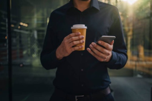 businessman holding takeaway coffee and smartphone - junk food stock pictures, royalty-free photos & images