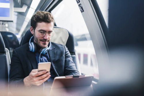 businessman in train with cell phone, headphones and tablet - travel stock pictures, royalty-free photos & images