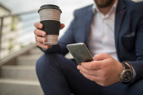businessman using smartphone and drinking take away coffee at the city - junk food stock pictures, royalty-free photos & images