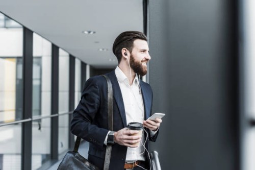 businessman walking in office building while talking on the phone with ear phones - junk food stock pictures, royalty-free photos & images