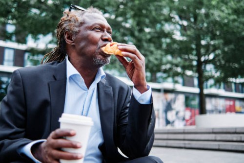 businessman with disposable cup eating croissant - junk food stock pictures, royalty-free photos & images